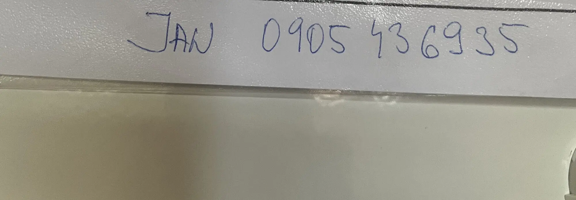 Telefónne číslo napísané rukou na vnútornej strane dvierok domového rozvádzača